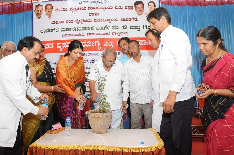 Guests water a potted sapling at a free health camp in Davangere.