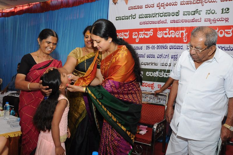 A trust representative gives a young girl a dose of medicine at a health camp.