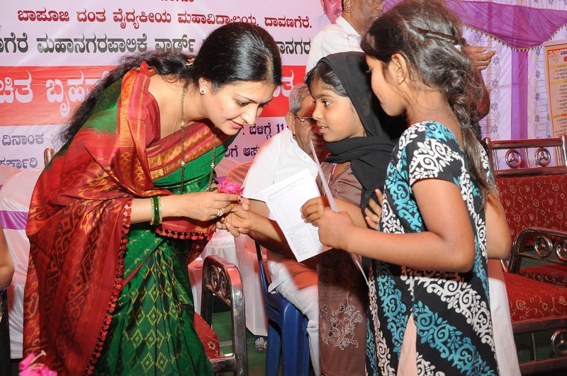A trust representative greets two girls at a health camp.