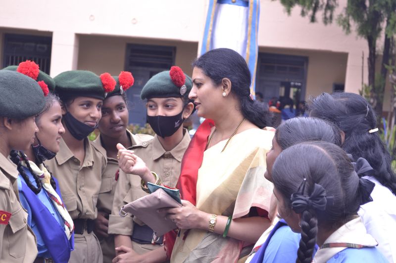 Schoolgirls in NCC uniform listen to a trust representative outside their school.