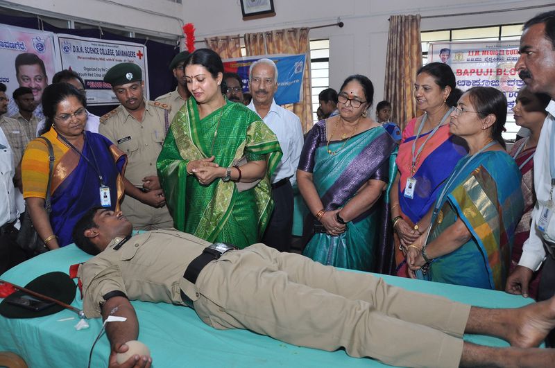 Trust representatives look on as a police officer donates blood.