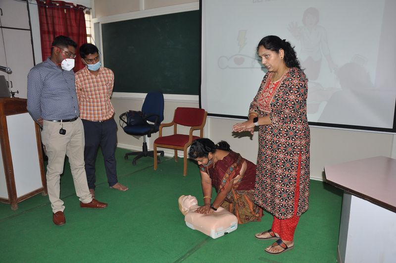 A trainee practises chest compressions on a CPR manikin while the instructor watches.
