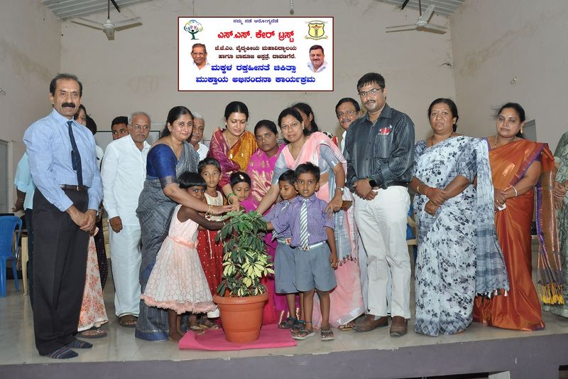 Children and guests water a potted plant to open the children's anaemia programme.