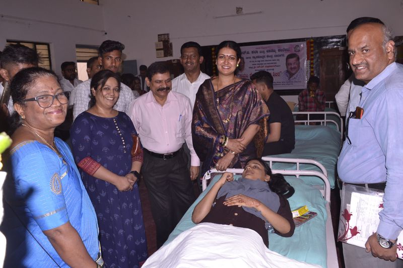 Trust representatives and doctors smile beside a young woman donating blood.