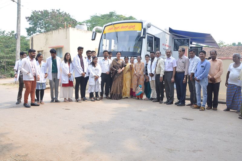 Doctors, students and staff line up beside the mobile health clinic bus in a village.
