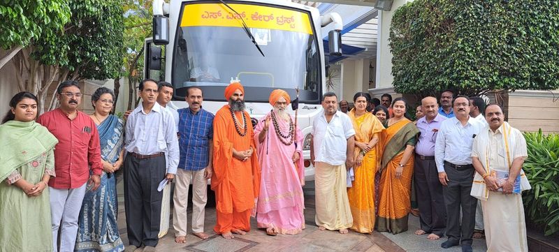 Guests and spiritual leaders stand in front of the SS Care Trust mobile health clinic bus.