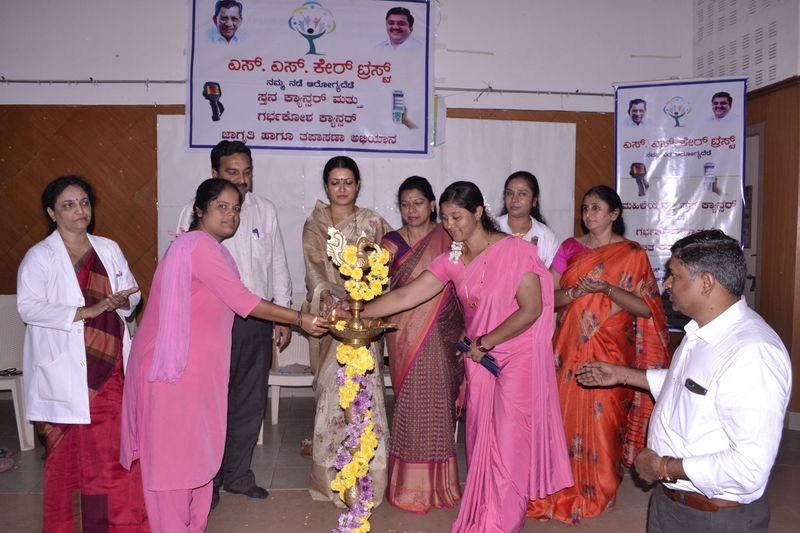 Doctors and trust representatives light a lamp to open a breast and cervical cancer awareness campaign.
