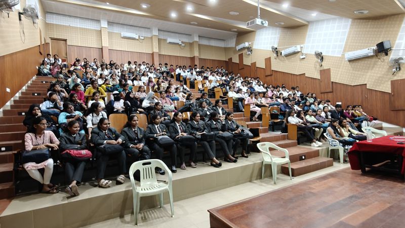 Students in blazers fill the tiered seats of a lecture hall.