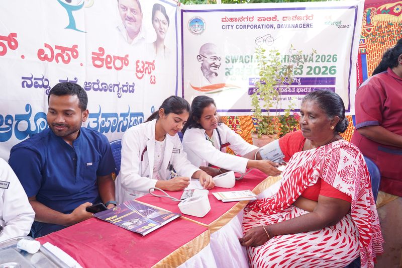 Doctors check a woman's blood pressure and note the readings at an SS Care Trust health camp held with Davangere City Corporation.
