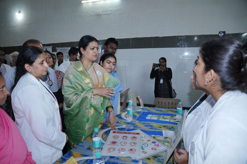 A visiting guest discusses health-awareness charts with medical students at an SS Care Trust health camp.