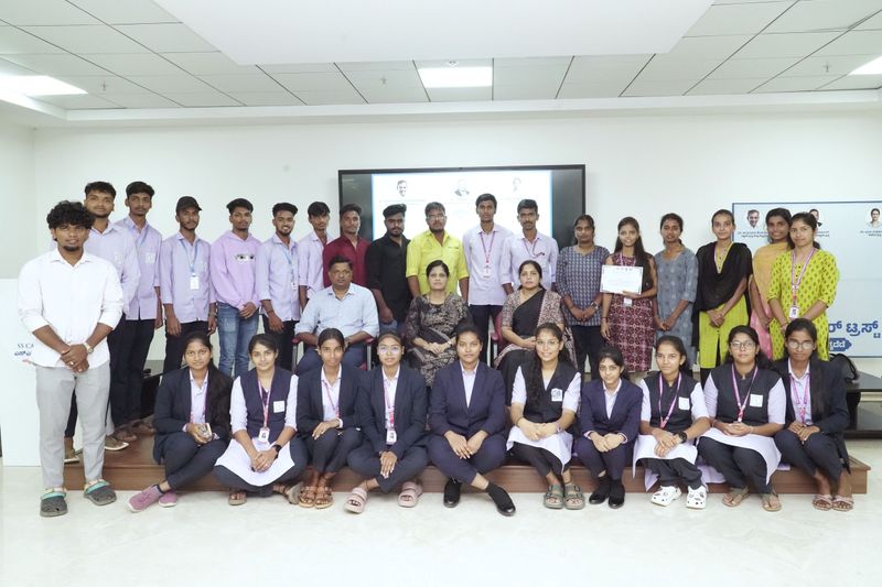 A group of trainees and staff pose together, with one holding a certificate, after a training session.