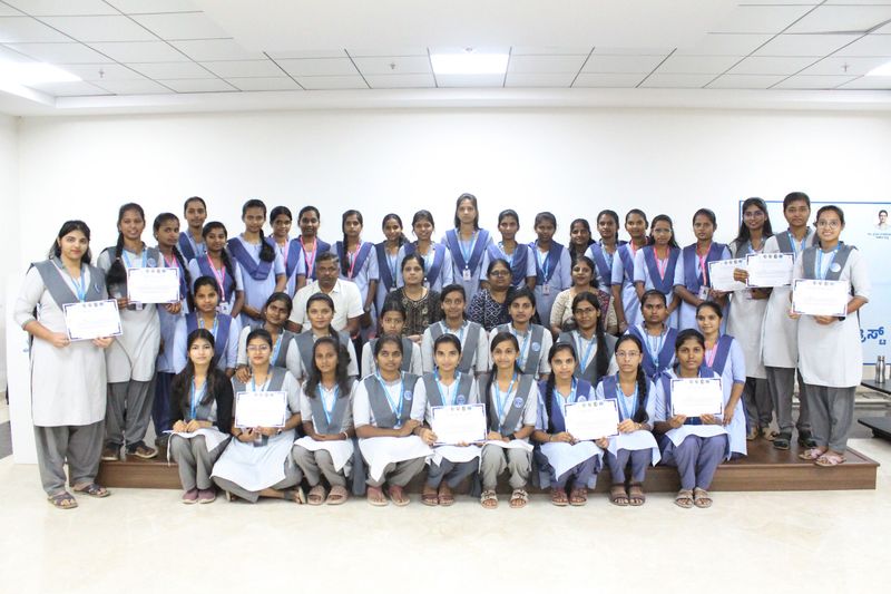 A large group of schoolgirls and teachers pose together holding certificates after completing a first aid training programme.