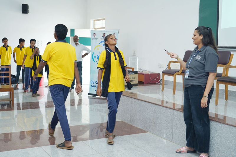 Students and a facilitator take part in a playful activity in a Kaushalya programme hall.