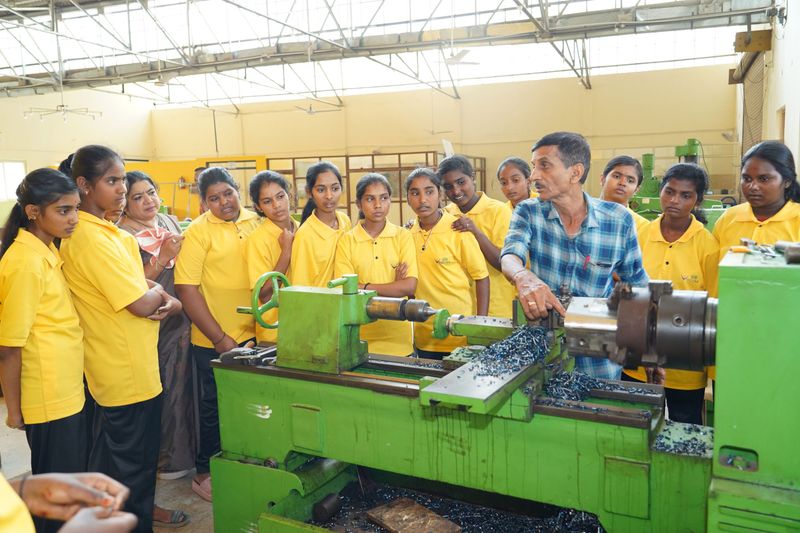 Students watch closely as an instructor operates a workshop lathe during a Kaushalya skills-training session.