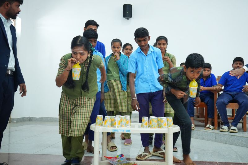 Students play a lively team game with cups on a table as a mentor looks on during a program activity break.