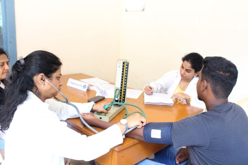 A doctor checks a young man's blood pressure while a colleague records details at a pre-donation health screening.