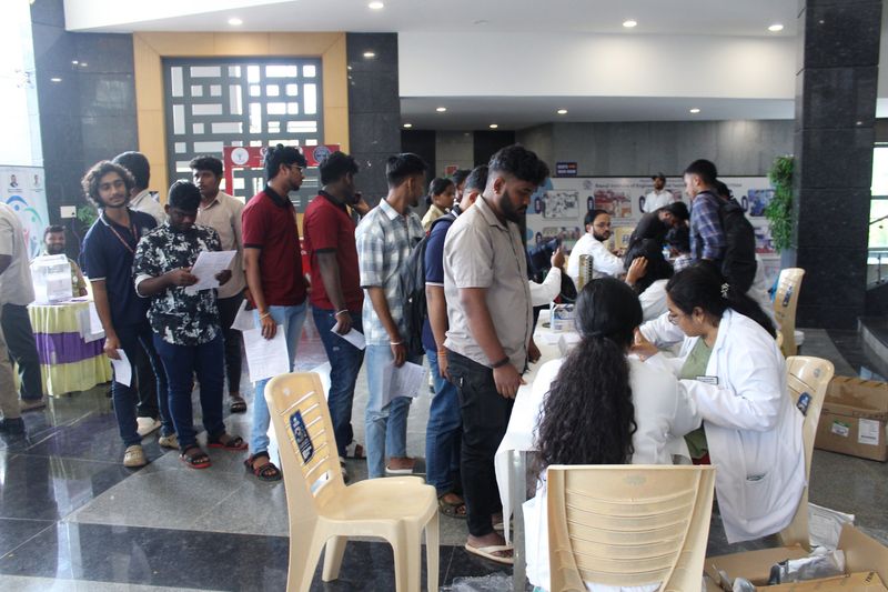 Young volunteers line up with registration forms as staff in white coats enrol them for the blood donation camp.