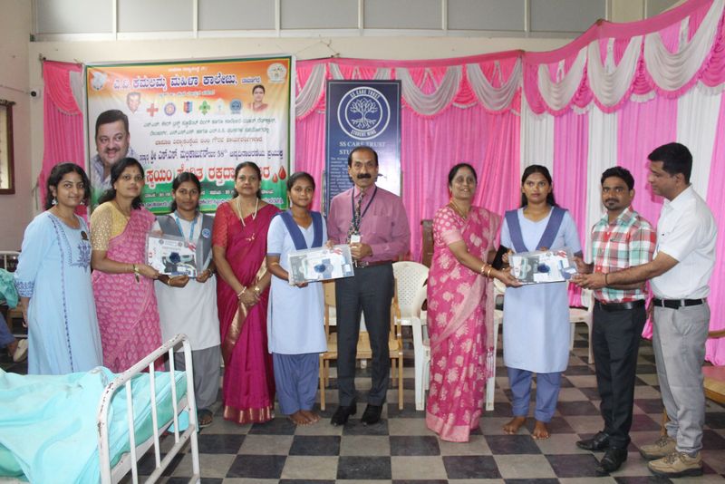 Women receive donor appreciation gifts from organisers on a decorated stage during an SS Care Trust Student Wing event.