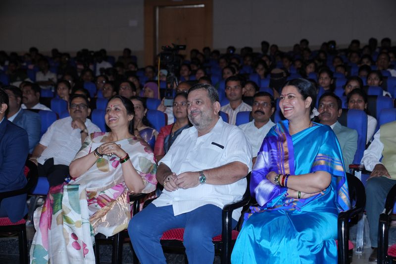 Guests in the front row of a packed auditorium smile during a Sankalpa programme event.