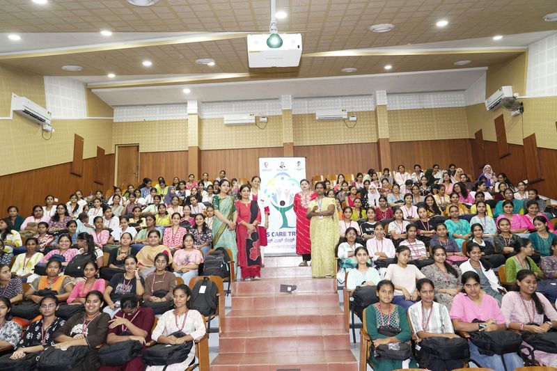 Dignitaries stand before a packed auditorium of young women at a health programme event.