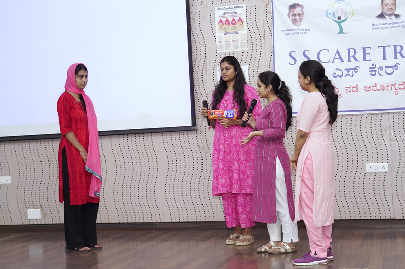 Young women take turns speaking into a microphone during a menstrual health awareness session at SS Care Trust.