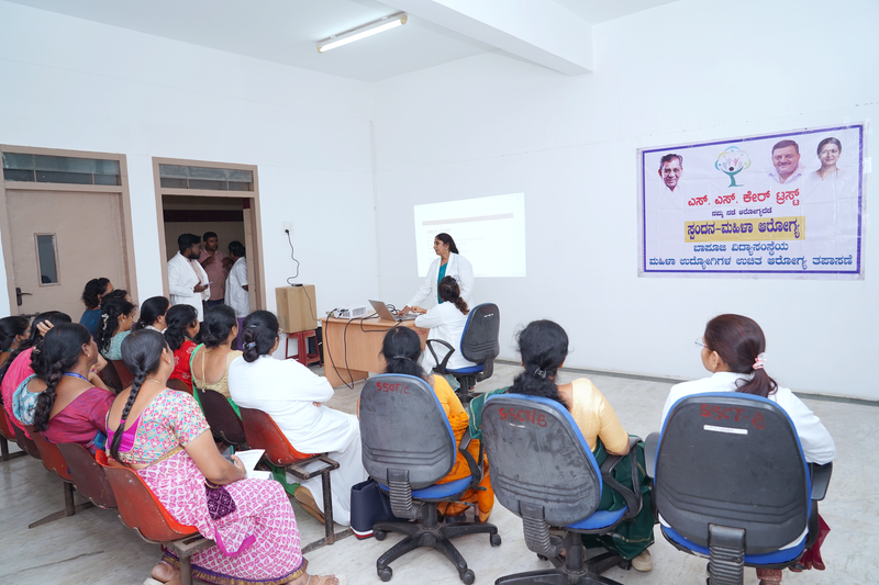 Women sit before a projector screen during a women's health training session under an SS Care Trust banner.