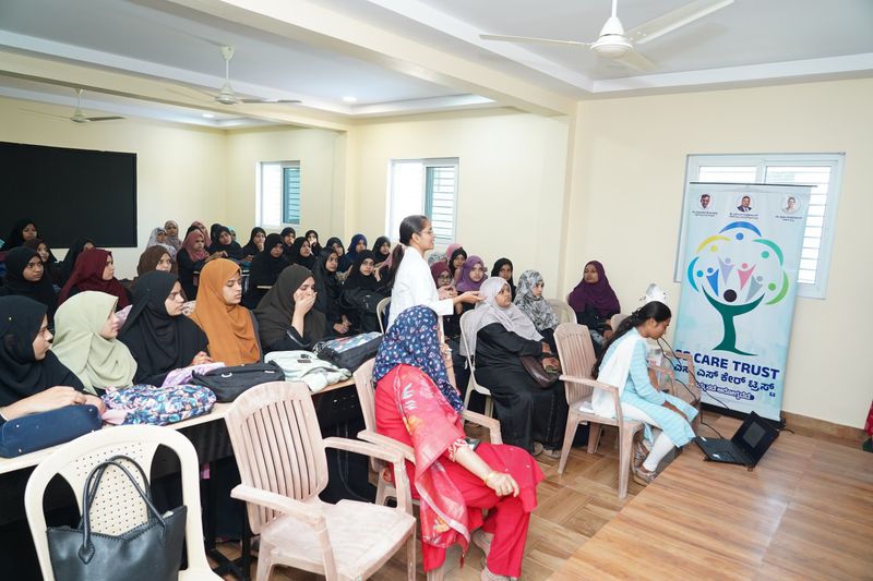A health worker presents to a large group of seated women during a women's health awareness talk.