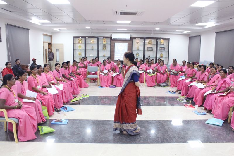 ASHA workers in pink sarees sit in a training circle as a facilitator speaks at an SS Care Trust women's health session.