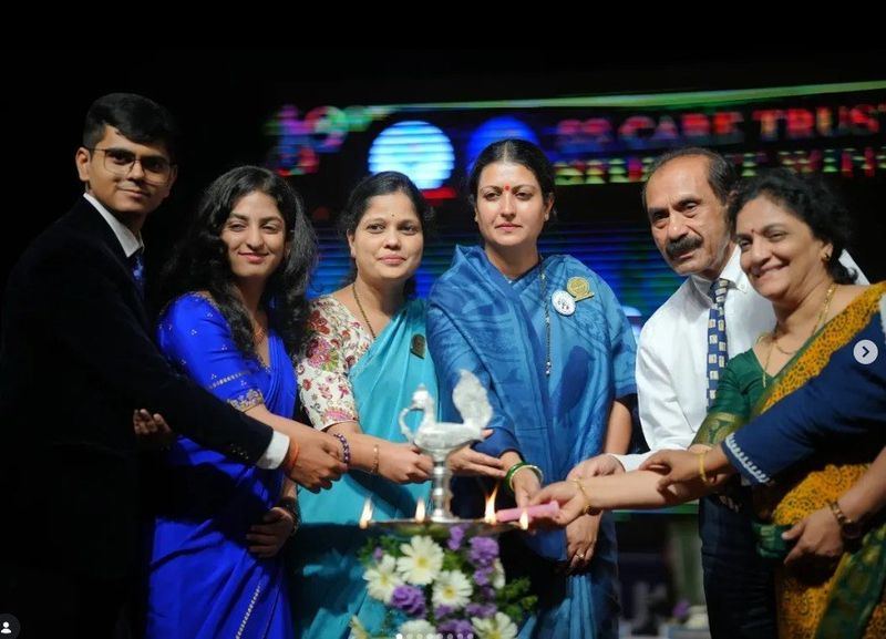 Trustees and officials light a ceremonial lamp on stage at a Student Wing event, with a banner visible behind them.