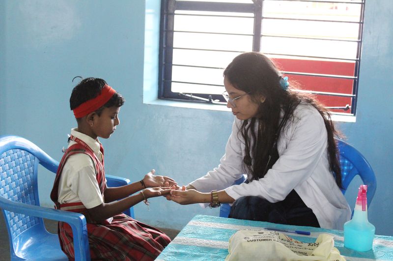 A health worker examines a schoolchild's hands and nails as part of a screening for anaemia.